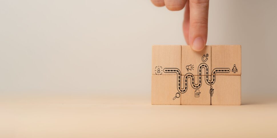 Three wooden puzzle blocks featuring symbols, illustrating AI's role in enhancing customer journey mapping.